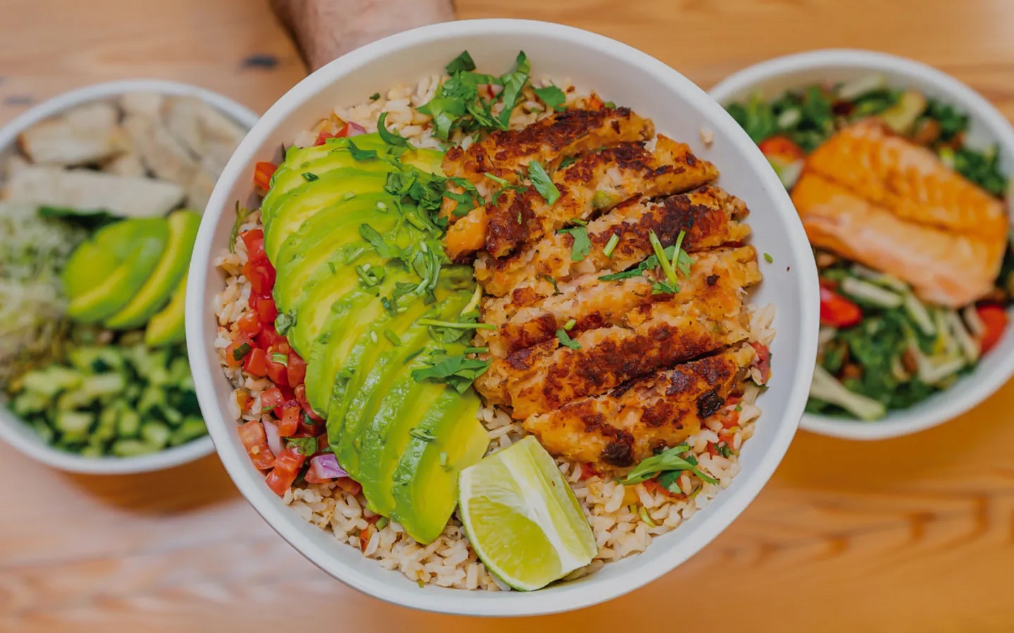 Avocado and chicken rice bowl with lime and diced tomato garnish