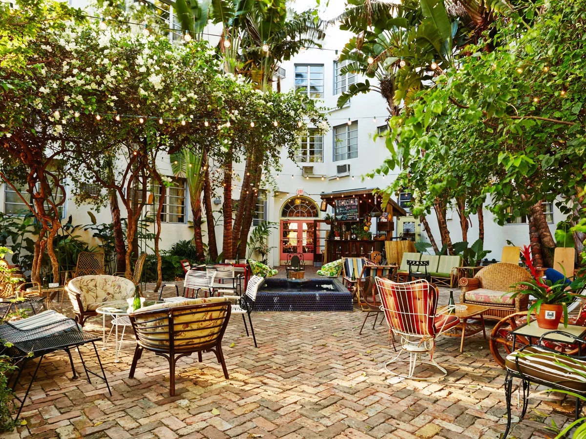 outside patio seating on brick pavers shaded by a barrier of trees